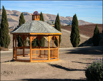 12 Cedar Octagon Belle Roof Gazebo shown with Red Cedar Deck,  2 x 2 Decorative Spindle Railings, Decorative Posts, Decorative Braces, Cupola, Top Railing Sections, Old English Pewter Asphalt Shingles, Clear Stain/Sealer and 4 x 4 Runners