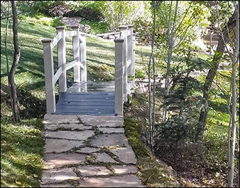 3 x 10 Double Rail Pedestrian Trail Bridge shown with Winchester Gray Trex Deck, White Vinyl Railings, Arctic White Highwood Beam Wrap, 36" High Rails, and Customer Supplied Post Caps.