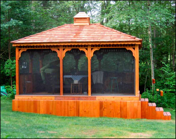 Custom 12x16 Cedar Rectangular Gazebo shown with Cedar Composite Deck, Solid Bottom Railings (no rails in front), Cupola, Screens with  Screen Door, Cedar Shake Shingles, 2 Coats of Cedar Stain Sealer and Customer Built Base. 