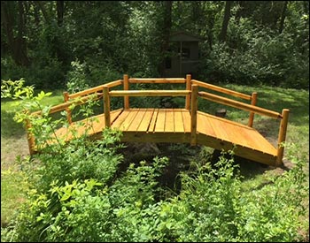 5 x 12 Treated Pine Log Rail Bridge with White Cedar Posts and Railings shown with Customers Stain/Sealer.
