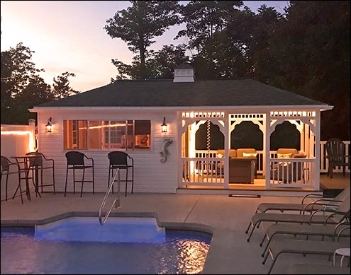 12 x 24 Vinyl Pool House shown with White Siding and Trim, Brown Composite Decking, Driftwood Asphalt Shingles, Cupola, and Concession Window with Bar. Lighting supplied by customer.